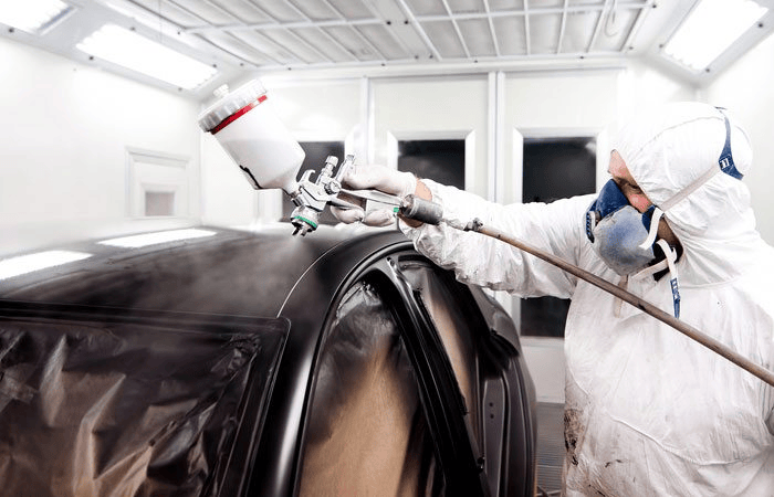 man spraying black car | <strong>Closed Door Respray: Solutions to Your Auto Body Painting Needs</strong> | GIASR